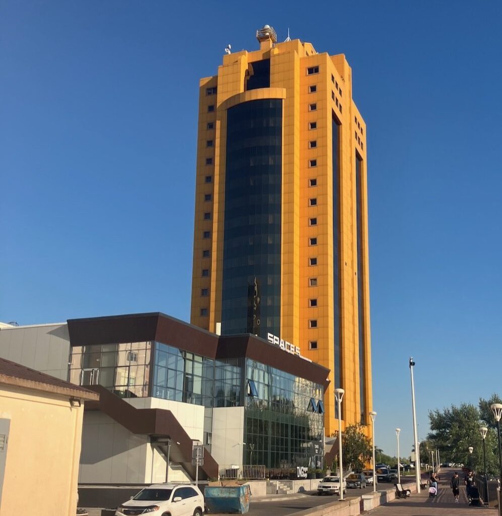 Astana cityscape: Tall yellow building with glass facade under a clear blue sky in Astana, Kazakhstan.