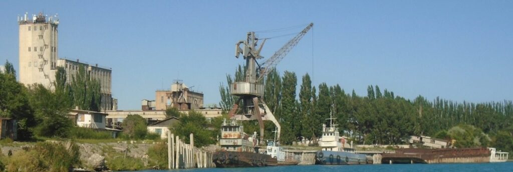 Balykchy port shipyard view with crane, ships, and industrial buildings along the shore of Issyk-Kul lake in Kyrgyzstan.