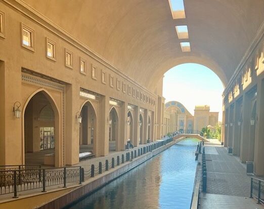 Turkistan architecture: Arched walkway with canal. Explore Turkistan's unique building design and waterways. Travel destination.