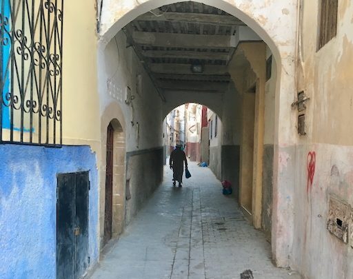 Salé, Morocco: Narrow street view with arched passage and a person walking in the distance. Authentic Moroccan architecture.